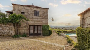 A stone building with a tiled roof, a pool, and a view of the countryside. - Quinta Stº António | Palheiro B | Monção | Rural Tourism | Pool (Monção)