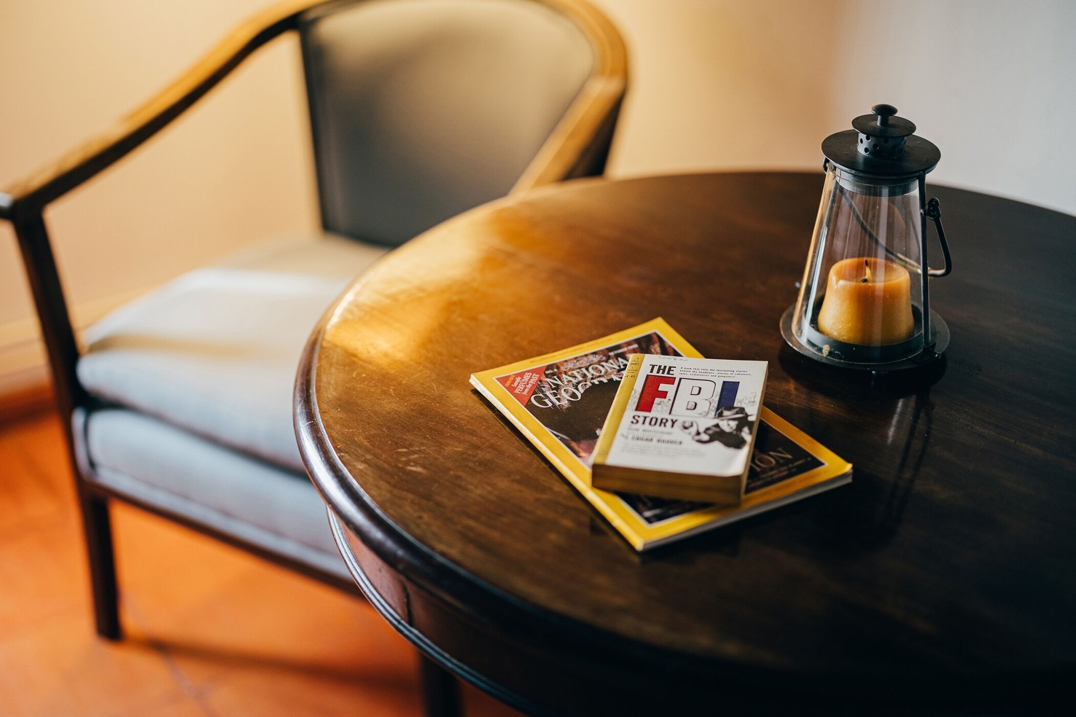 Una mesa de madera redonda con una vela y dos libros.