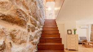 Eine Treppe mit Holzdielen führt zu einer Zwischenebene, begrenzt von Steinwänden.