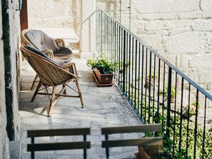 A balcony with wicker chairs and a potted plant.