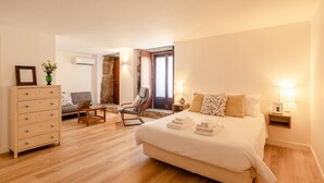 Ein Schlafzimmer mit Bett, Kommode, Sessel, Schreibtisch und Nachttisch.