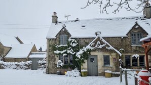 Un edificio de piedra con techo nevado y un pequeño jardín.