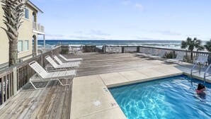 Un espace piscine avec des chaises longues et vue sur l’océan.