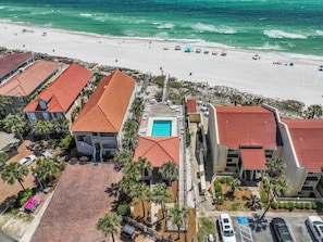 An aerial view of a beachfront hotel with multiple buildings, a swimming pool, and a beach with umbrellas and lounge chairs. - Come Be At Peace! Spacious 3 Bd/3ba Beach Home! Sleeps 10! (Panama City Beach)