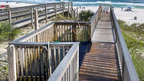 Une promenade en bois qui mène à une plage d’où l’on a une vue dégagée sur l’océan.