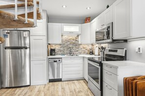 Una cucina moderna con mobili bianchi, elettrodomestici in acciaio inossidabile, lavastoviglie e forno integrato.