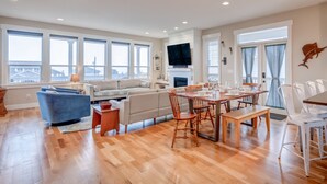 A spacious living room with a large sofa, a dining table with chairs, and a fireplace.