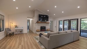 A modern living room with a grey sofa, a fireplace, and a television. - Mid-century Modern Remodel near Pisgah & Asheville (Asheville)