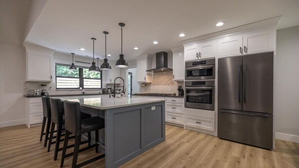 A modern kitchen with white cabinets, stainless steel appliances, and a central island with bar stools. - Mid-century Modern Remodel near Pisgah & Asheville (Asheville)