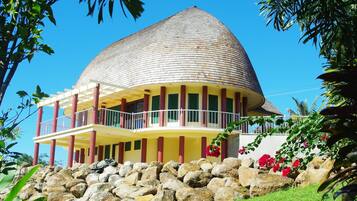 A building with a curved roof, a balcony, and a stone base.