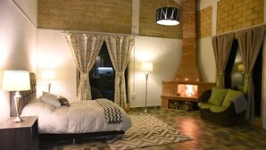 A bedroom with a bed, two bedside lamps, a patterned rug, a fireplace, and a sofa. - Cabaña El Encino en Real del Monte (Mineral del Monte)