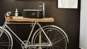 A bathroom with a bicycle mounted on a stand, a sink, a mirror, and a towel rack. - Cabaña El Encino en Real del Monte (Mineral del Monte)