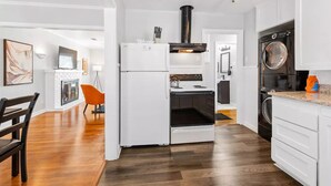 Una cocina moderna con muebles blancos, horno empotrado, estufa y lavavajillas.