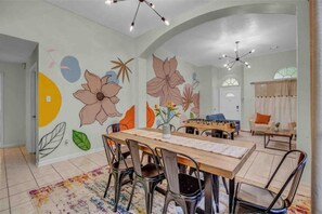 A dining area with a wooden table, chairs, and a floral mural on the wall.