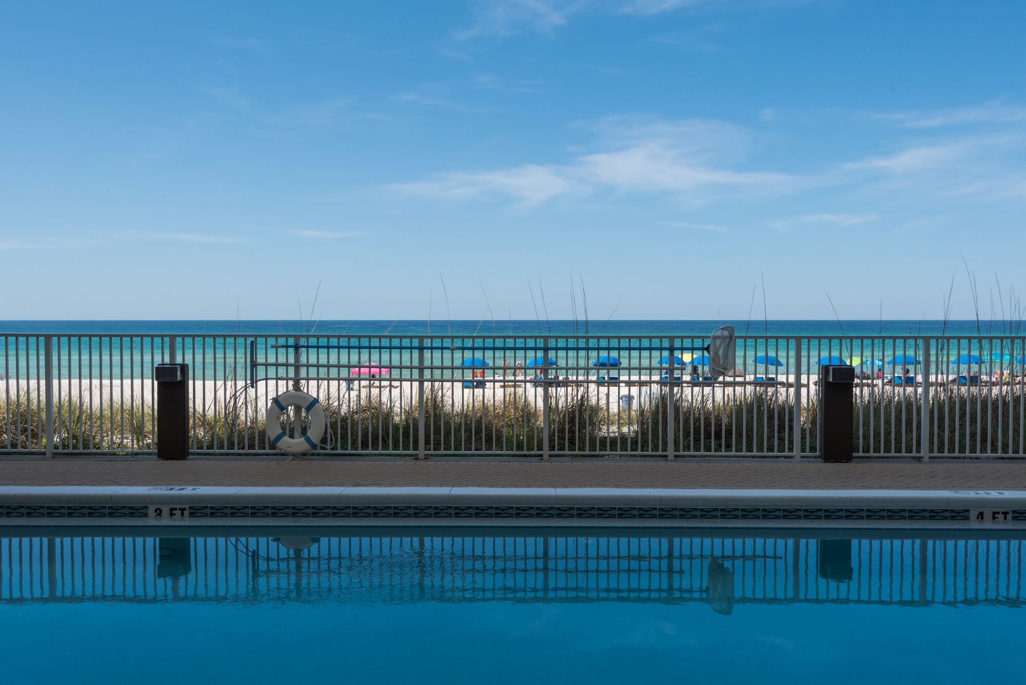 Piscina con vista a una playa y una valla.