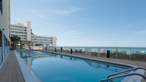 Ein Pool mit Blick auf den Strand und ein Gebäude im Hintergrund.