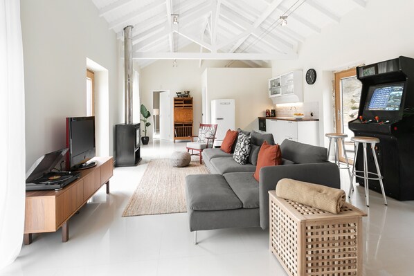A spacious living area with a modern sofa, a television, and a gaming console.