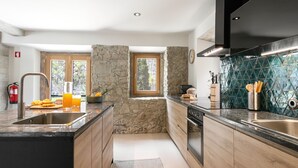 Une cuisine moderne avec un mur d’accent en pierre, des armoires en bois et un grand îlot central doté d’un évier.