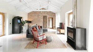 Un salon spacieux avec une cheminée moderne, un grand canapé et un fauteuil rouge.