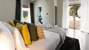 Une chambre avec un grand lit, une vue sur l’extérieur et une porte donnant sur un balcon.
