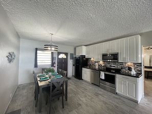 Enjoy meals in the kitchen with sleek cabinetry, a refrigerator, and microwave. Dine at the wooden table with pendant light above.