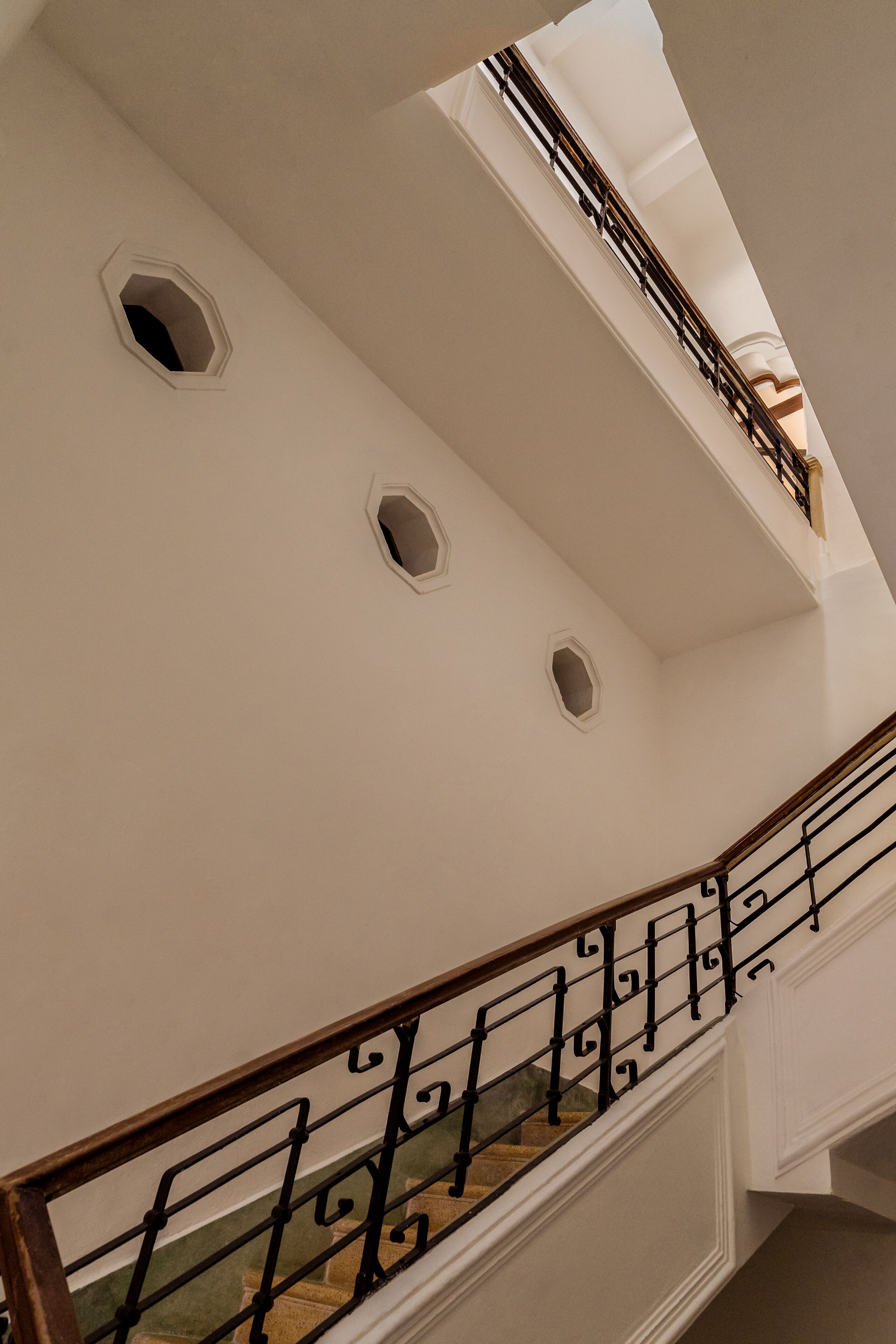 Eine Treppe mit geschwungener Handlauf und mehreren kleinen Fenstern.