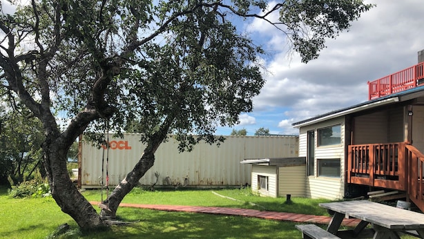 A house with a red deck, a picnic table, and a tree in the yard. - Bear Paw Inn (Dillingham)