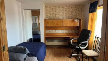 Habitación pequeña con literas, un escritorio y una silla, y un radiador.