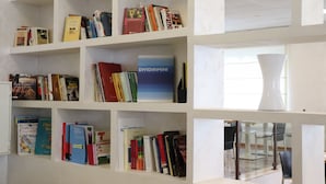 A bookshelf with various books and a vase. - Hotel Morolli Rimini (Rimini)