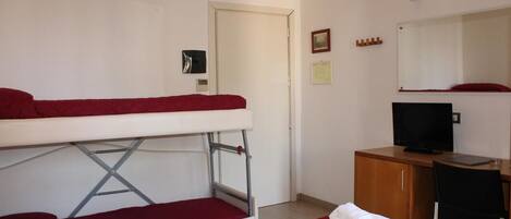 A hotel room with a bunk bed, a desk with a computer, a television, and a mirror.