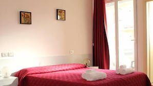 A hotel room with two beds, a window with red curtains, and a view of the outside. - Hotel Morolli Rimini (Rimini)