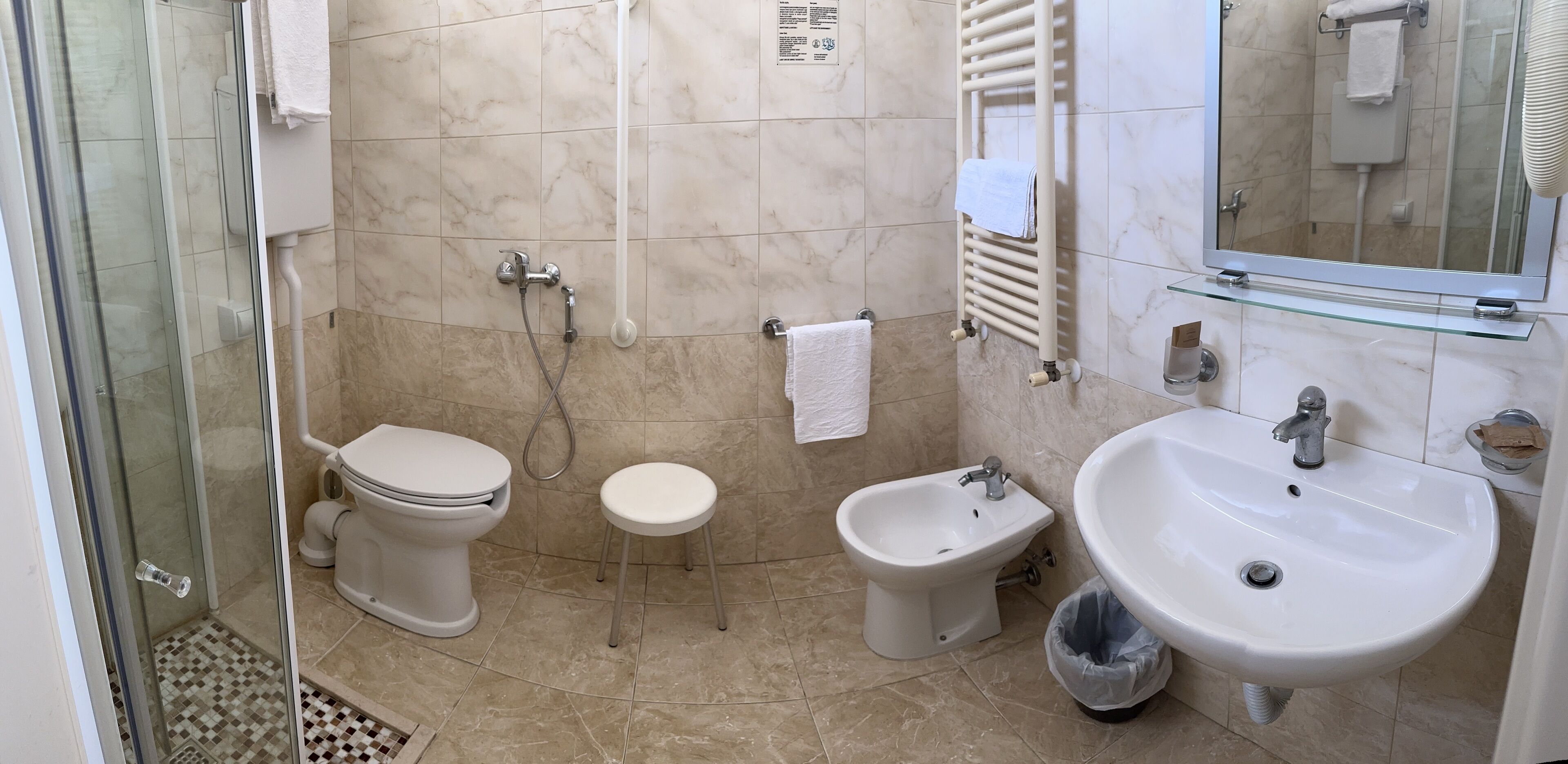 A bathroom with a toilet, bidet, sink, and glass shower enclosure.