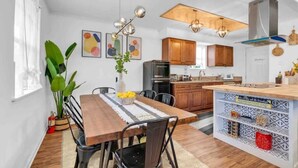 A modern kitchen with wooden cabinets, a central island, and pendant lighting.