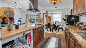 A modern kitchen with wooden cabinets, a large island, and a dining area with a table and chairs.