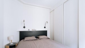 Un dormitorio con cama, lámparas de noche, mesita de noche y armario.