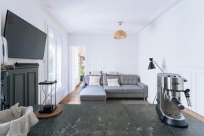 A modern living room with a sofa, a coffee machine, and a television.