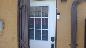 Una puerta principal con ventana, buzón y cuadro eléctrico en la pared.