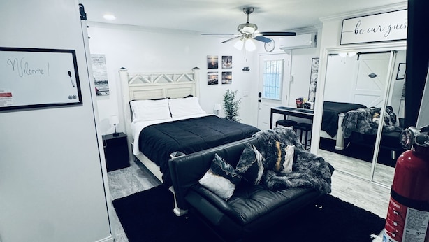 Un dormitorio moderno con una cama, un sofá, una mesita y un espejo.