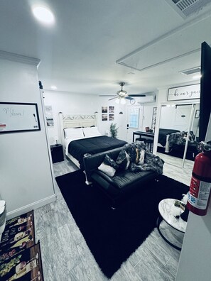 Un dormitorio moderno con una cama, un sofá, una mesita y un espejo.