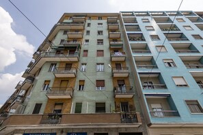 A multi-story residential building with balconies, a visible restaurant sign, and a clear sky. - Belfanti, 6 - Bright apartment with view (Milano)