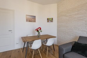 A small dining area with a wooden table, white chairs, and a vase of flowers. - Belfanti, 6 - Bright apartment with view (Milano)