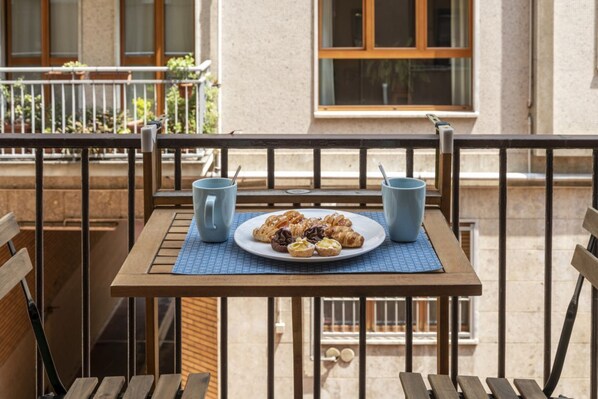 A balcony with a table set for breakfast, two blue cups, and a plate of pastries. - Strigelli, 13 - Accogliente bilocale con balcone (Milano)