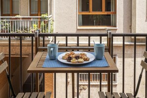 A balcony with a table set for breakfast, two blue cups, and a plate of pastries.