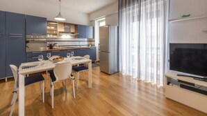 Uma cozinha moderna com área de refeições, uma televisão grande e vista para o exterior.