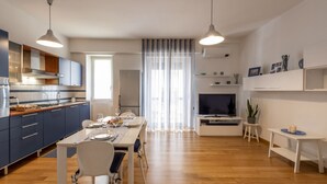 Uma cozinha moderna com área de jantar, TV e uma pequena mesa com objetos decorativos.