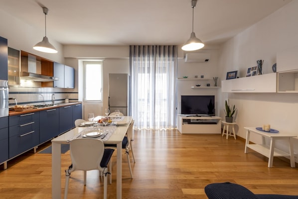 Una cocina moderna con comedor, televisor y una pequeña mesa con objetos decorativos.