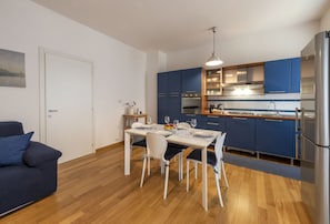 A modern kitchen with blue cabinets, a dining table with chairs, and a refrigerator.