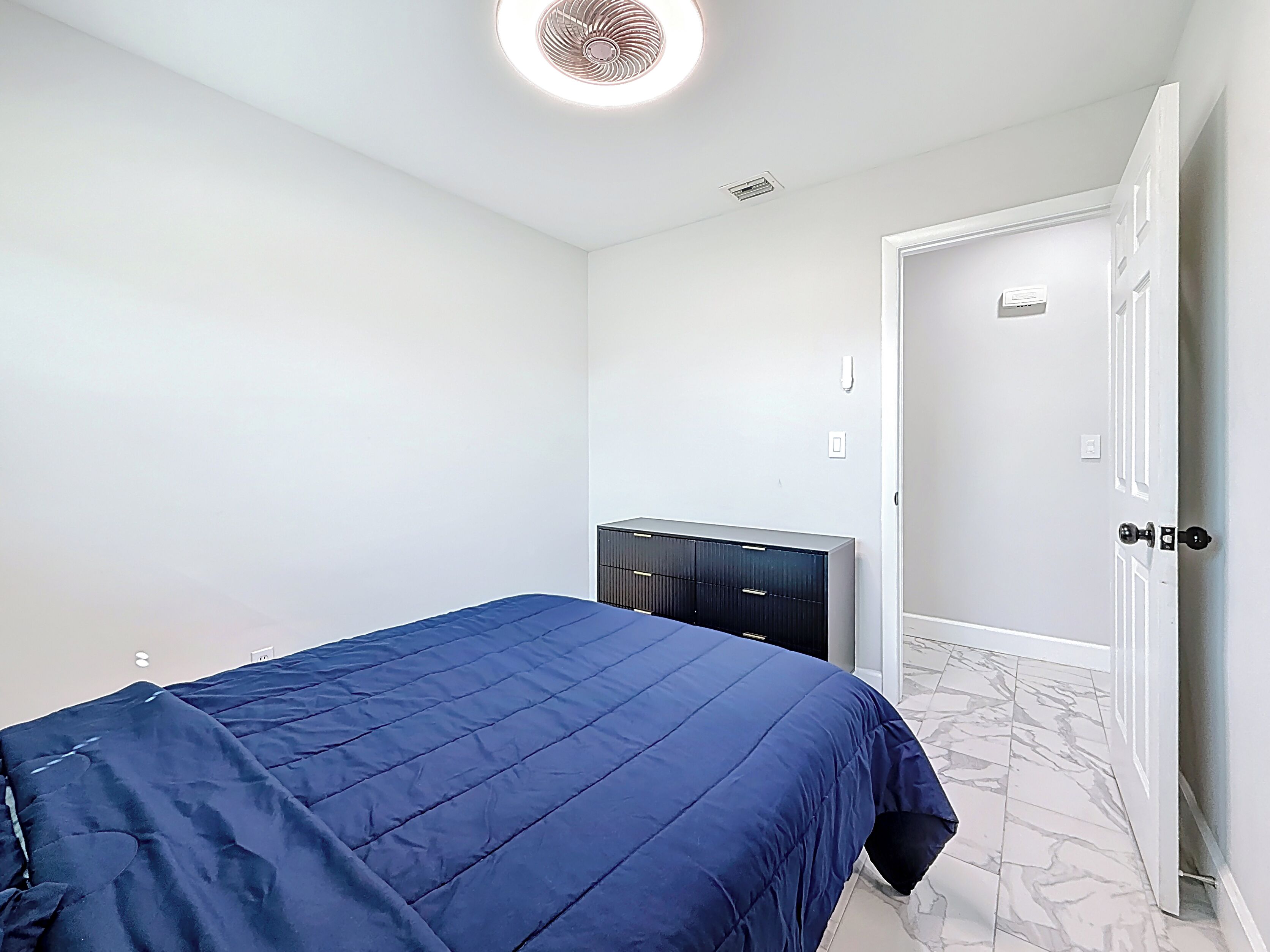 A bedroom with a bed, a dresser, and a door.