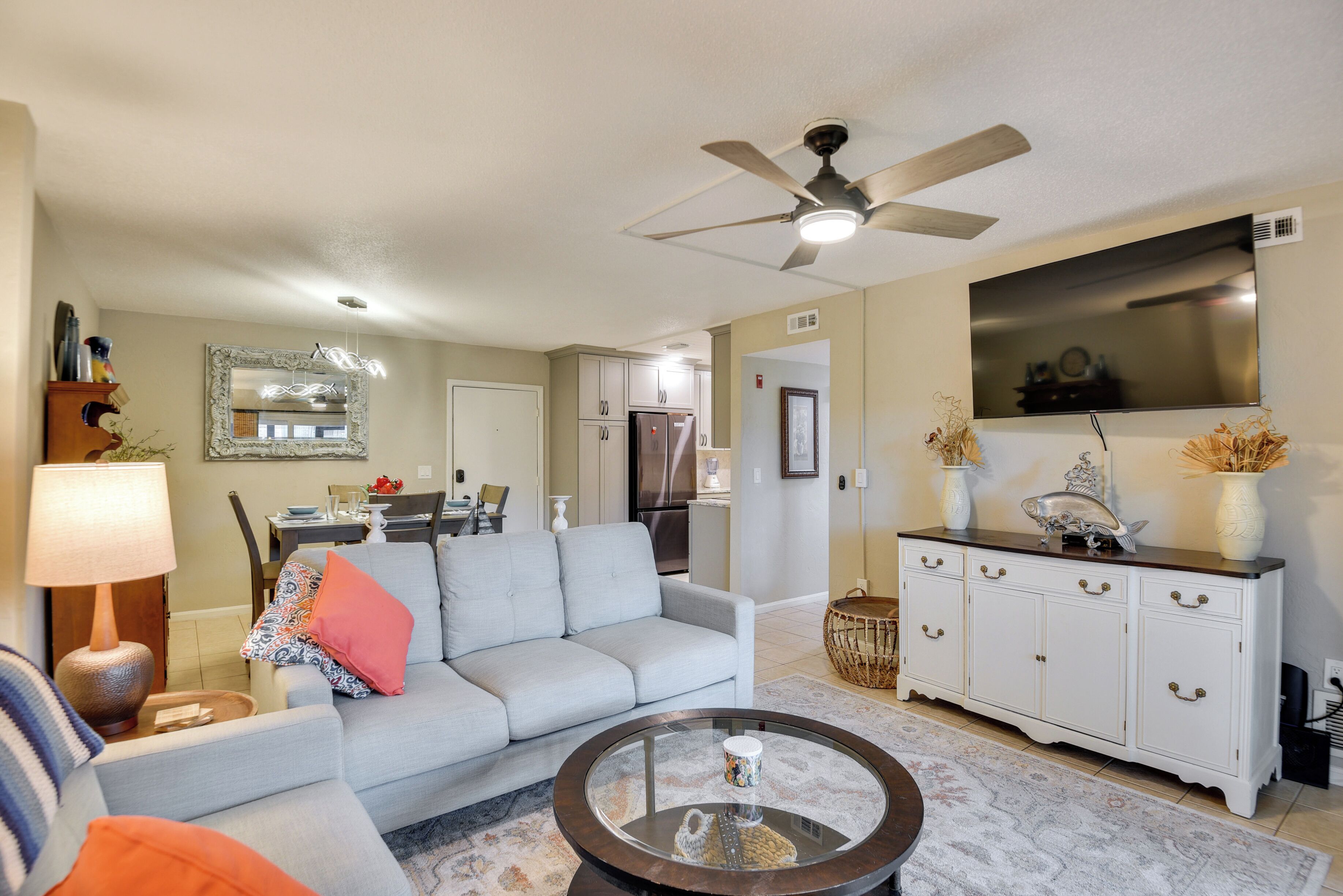 A living room with a sofa, coffee table, and a TV mounted on the wall.