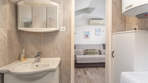 Une salle de bain avec un lavabo, un miroir et un meuble de rangement.